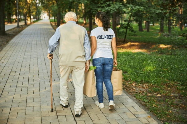 Volunteers assisting an elderly woman with groceries